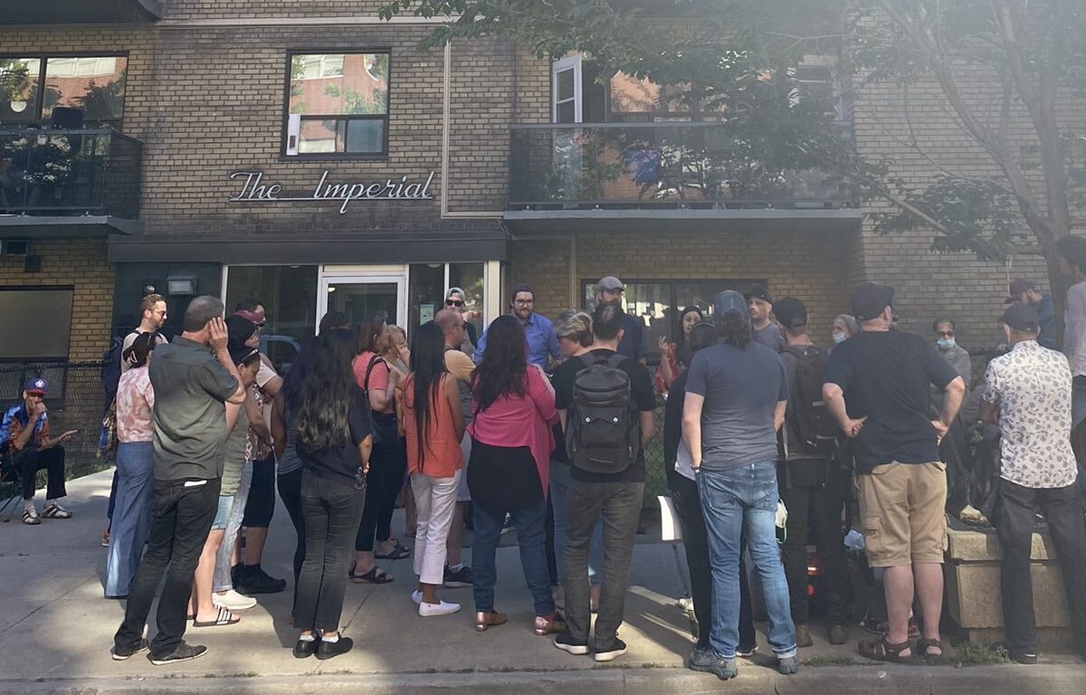 A photo of a group of people gathered outside an apartment building.