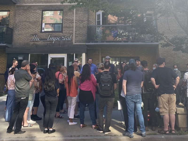 A photo of a group of people gathered outside an apartment building.