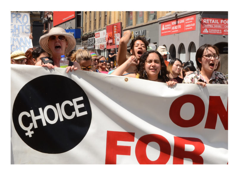 Women in the Toronto Dyke March hold a banner by the Ontario Coalition for Abortion Clinics reading "Choice". Photo: Mary Crandall.