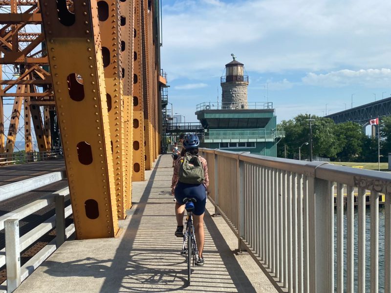 Cyclist riding on bike lane next to a bridge.