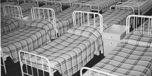 A photo of a line-up of beds in a residential school