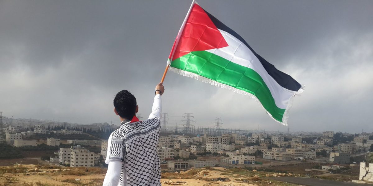 A photo of a man waving the Palestinian flag.