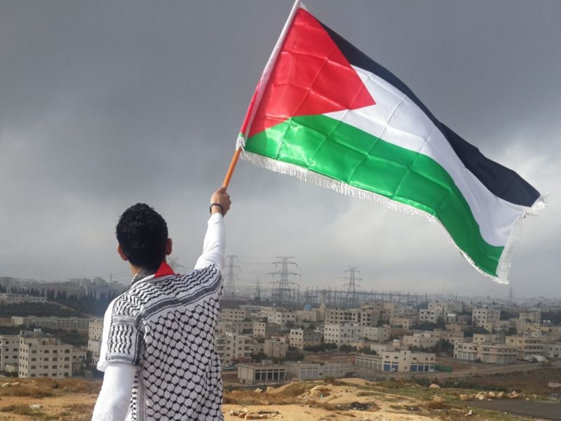 A photo of a man waving the Palestinian flag.