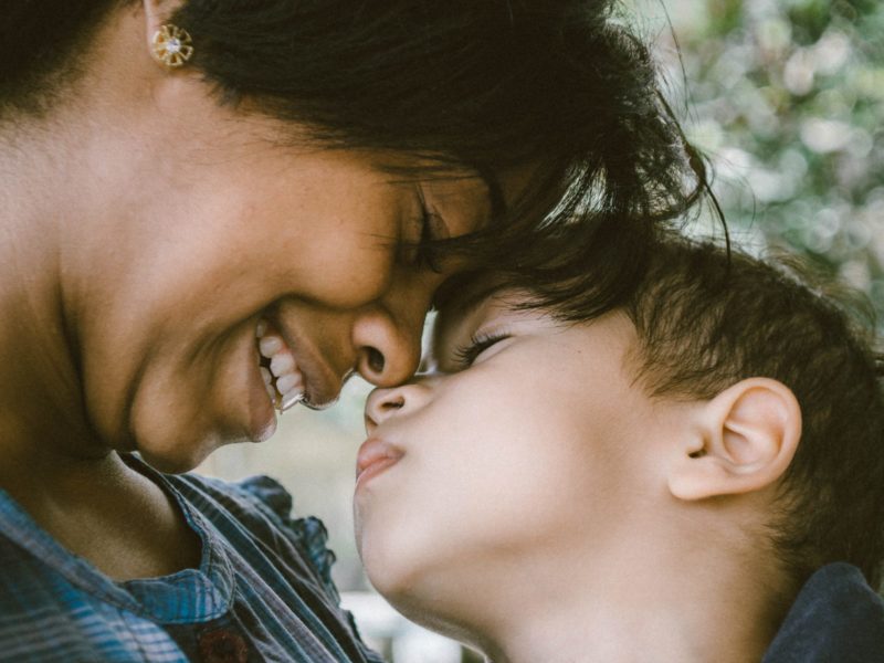 A photo of a mother and child smiling with their faces close together