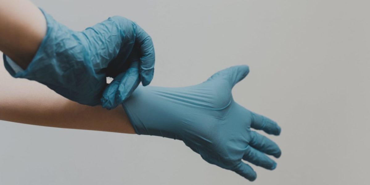 A photo of someone with blue medical gloves.