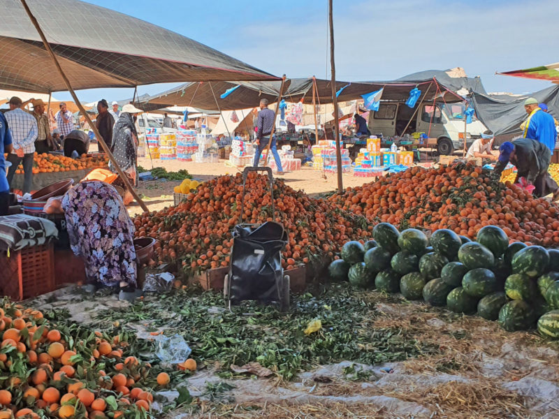 A photo of fruits and vegetables piled high on the ground at a vegetable market.