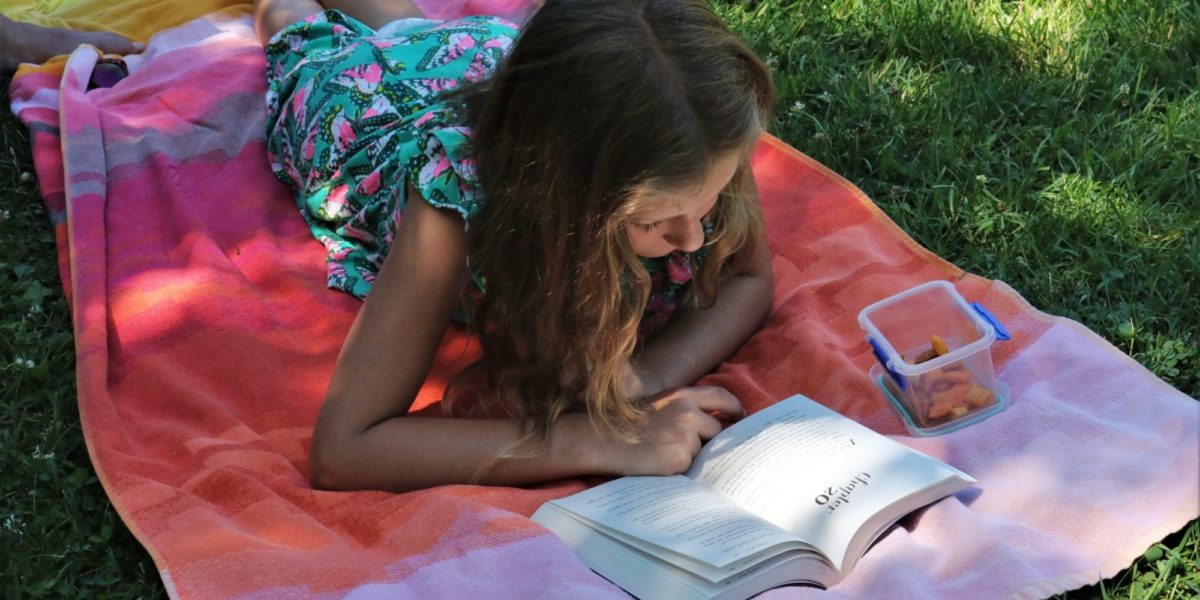 A photo of a young woman enjoying some summer reading.