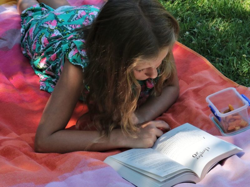 A photo of a young woman enjoying some summer reading.