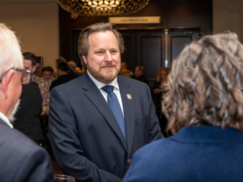 United Steelworkers union Director Marty Warren wearing a suit with a USW pin with people in the foreground he is talking with.