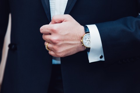 Executive pay deduction. Image of a person wearing an expensive watch and wearing a tuxedo.
