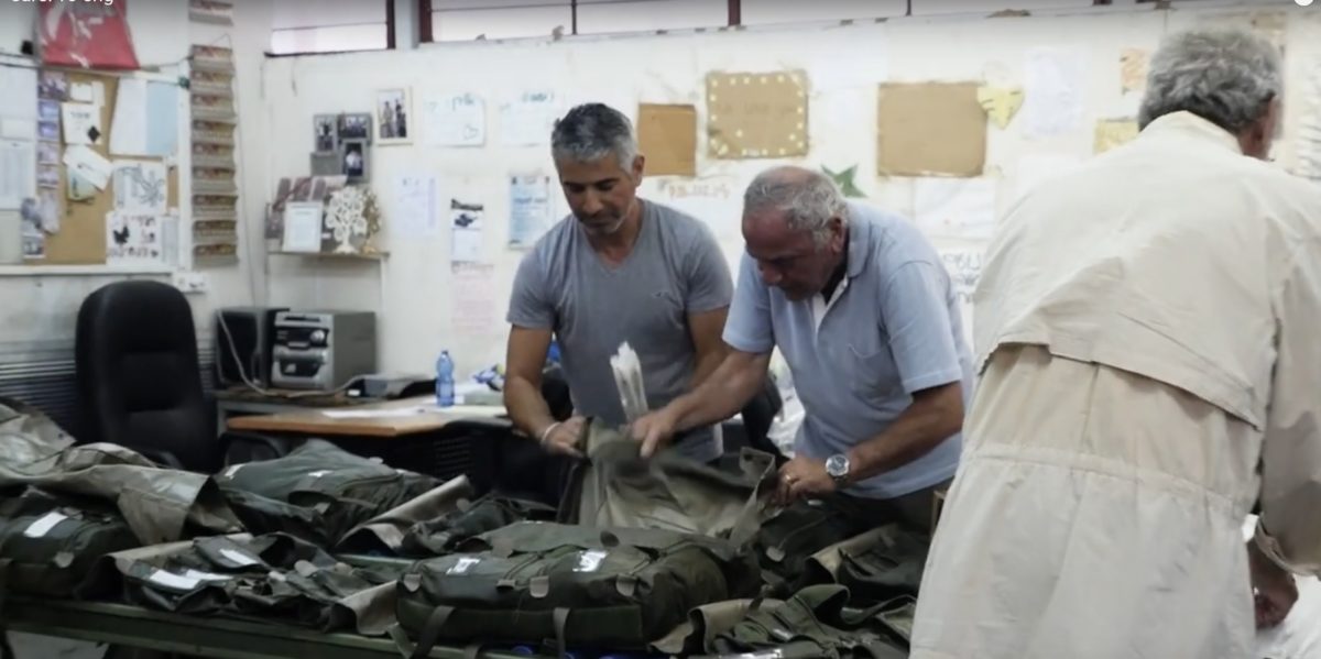 A screenshot from a Sar-El Canada promotional video showing volunteers preparing equipment for IDF soldiers.