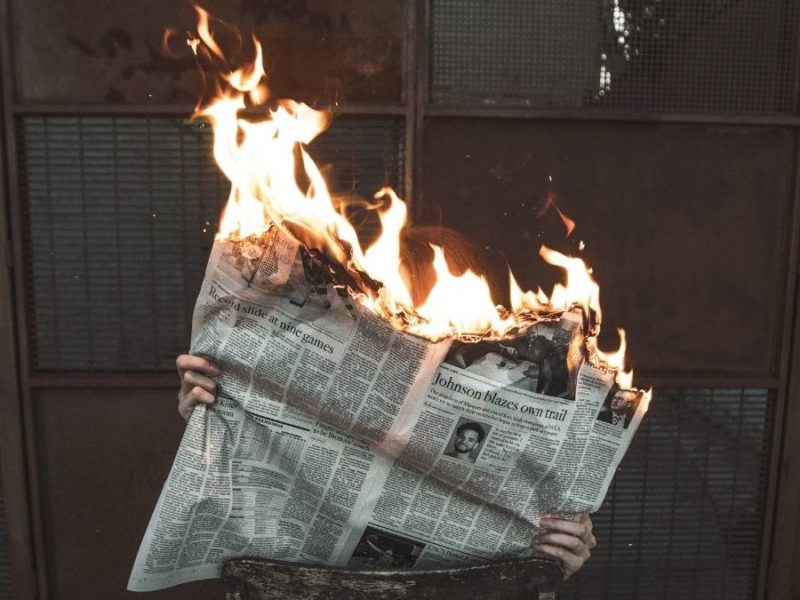A newspaper on fire, representing how corporate interests aren't in the public good