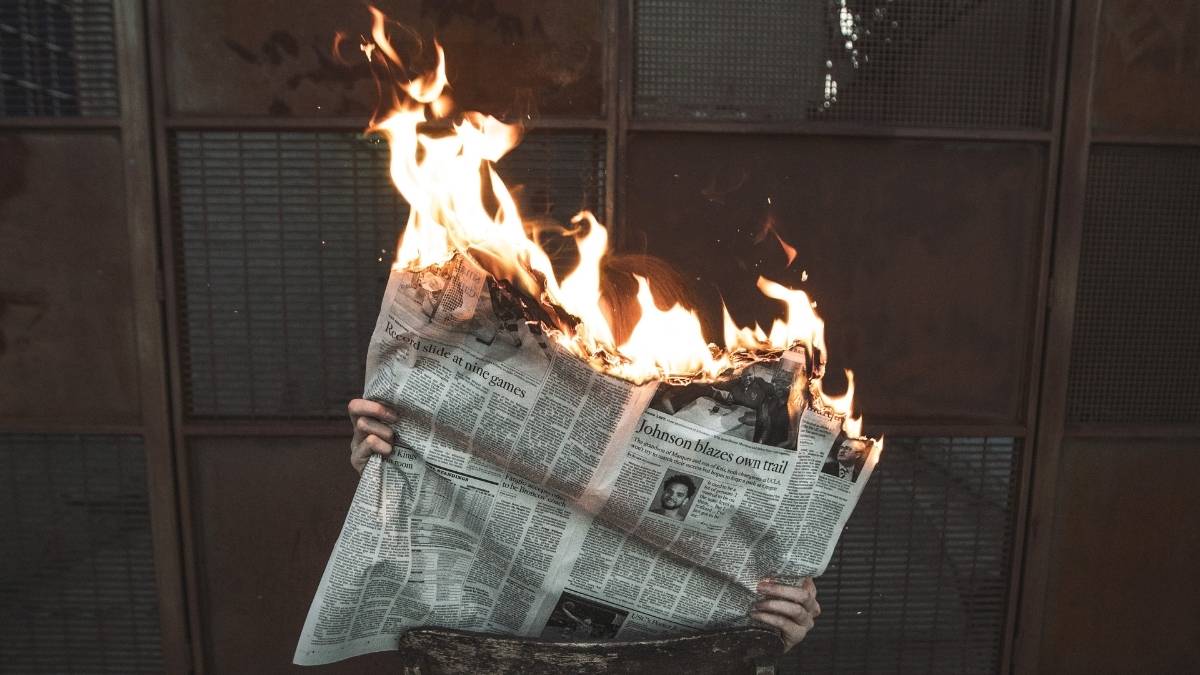 A newspaper on fire, representing how corporate interests aren't in the public good