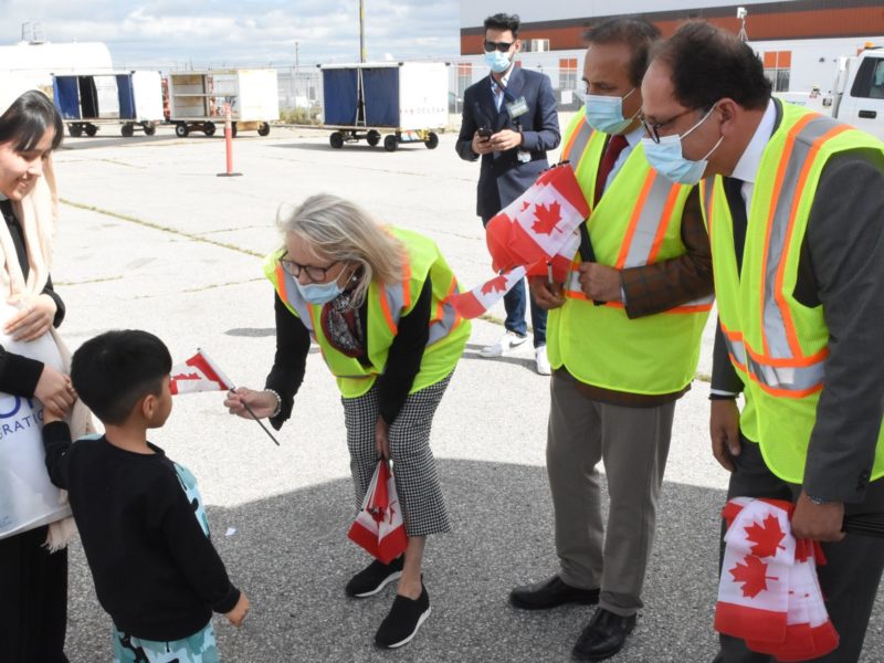 Immigrants being welcomed to Canada by representatives from Immigration Refugees and Citizenship Canada.
