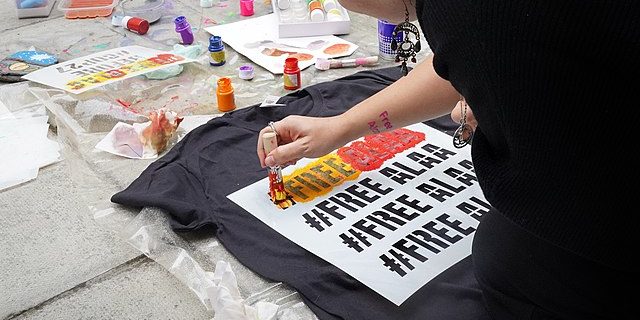 A photo of someone painting Free Alaa on a tshirt.