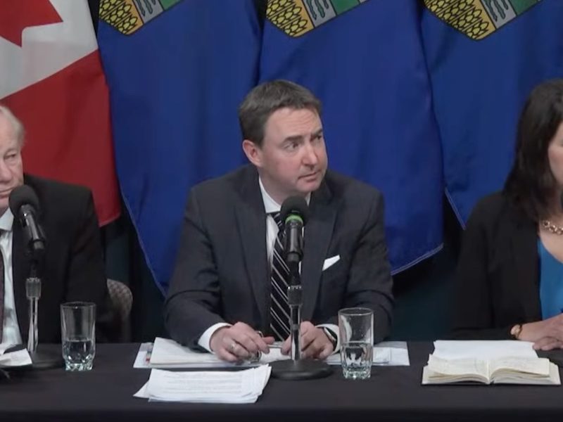 A screenshot of Dr. John Cowell, sole administrator of Alberta Health Services, Health Minister Jason Copping, and Premier Danielle Smith at yesterday’s news conference.