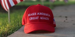 A photo of a Make America Great Again ball cap on a piece of sidewalk.