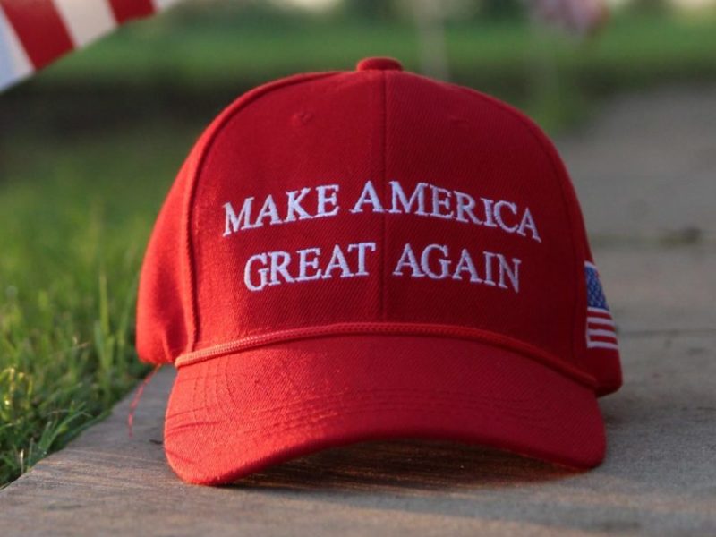 A photo of a Make America Great Again ball cap on a piece of sidewalk.