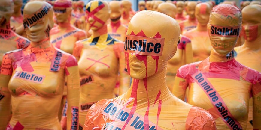 An image of orange mannequins with words on them that say, "Justice," "Do not look away," and "Do not be ashamed"