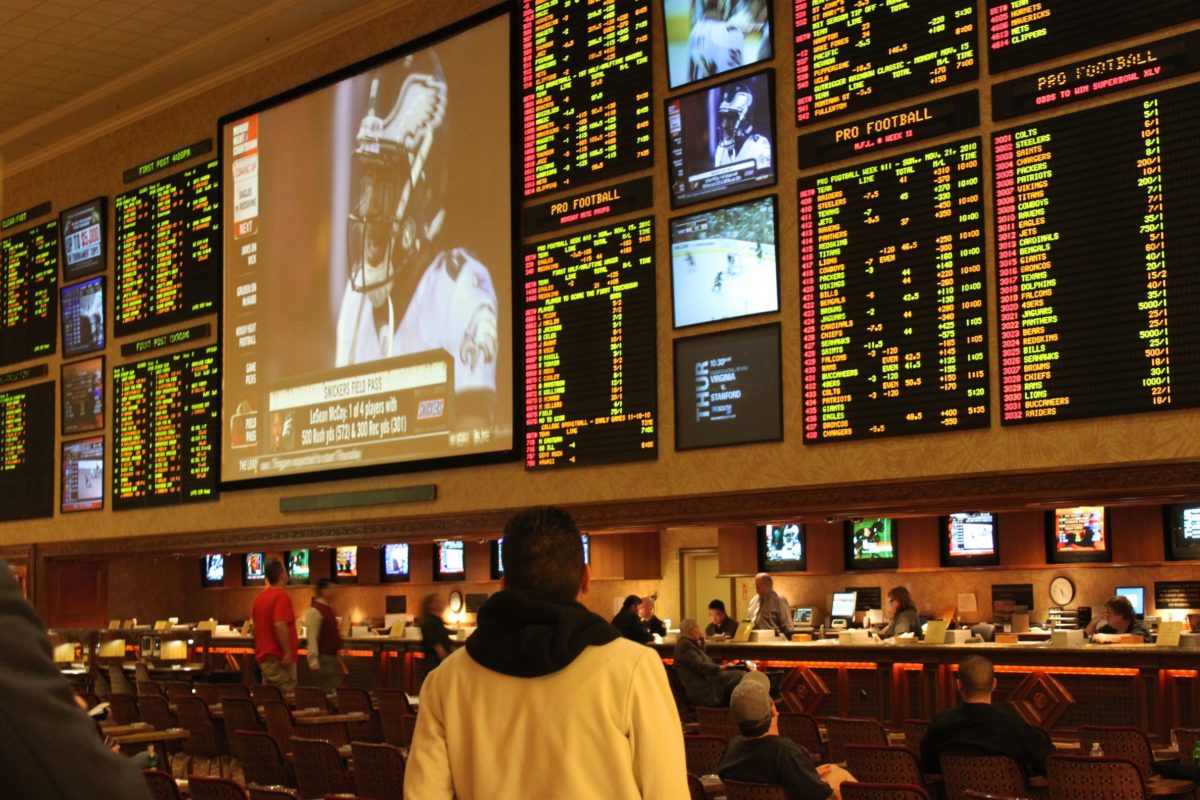 A photo of a person standing in front of an odds board at a race and sports gambling book in Las Vegas.