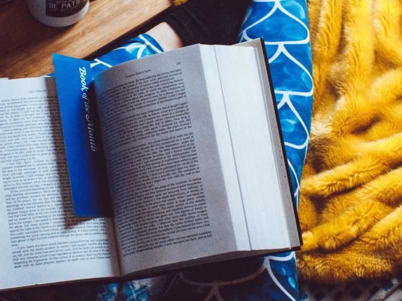 A book is settled on a table with a bookmark inside of two pages.