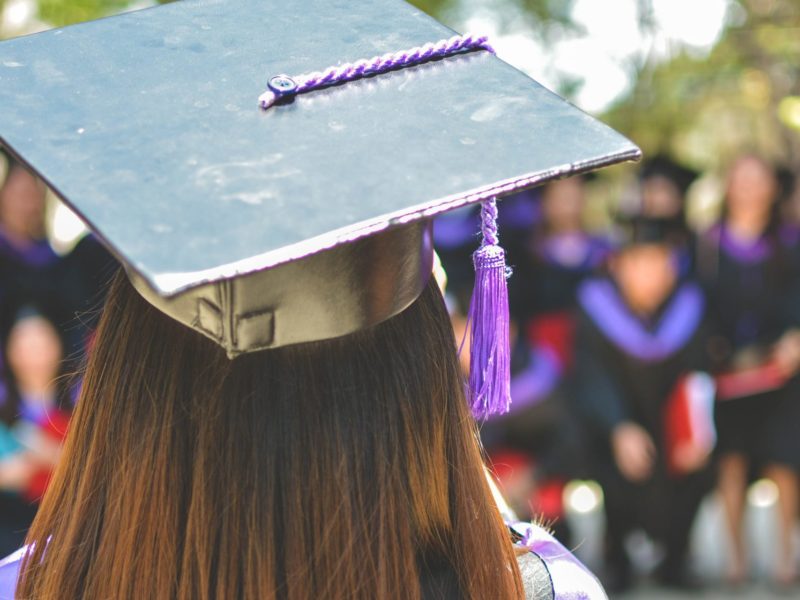 An image of the back of a young woman wearing a graduation cap.