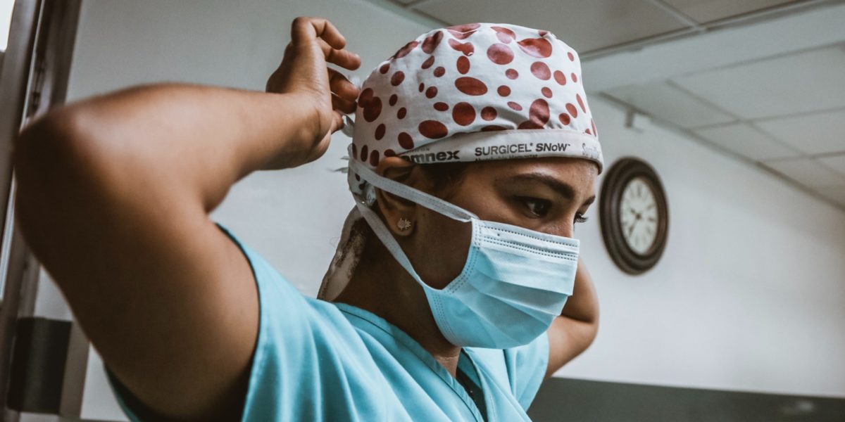 An image of a nurse adjusting their scrub cap