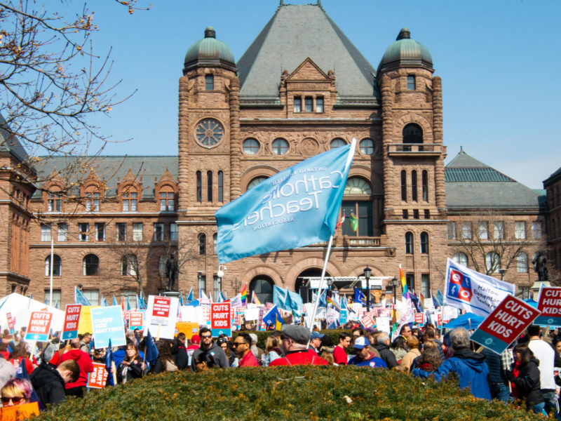 An image of a protest happening at Queen's Park in Toronto.