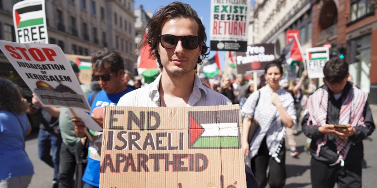 A protester holding a sign calling for the end of the apartheid practices of Israel's government.