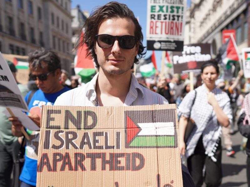 A protester holding a sign calling for the end of the apartheid practices of Israel's government.