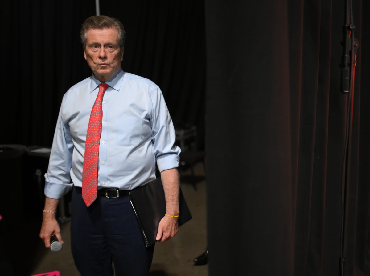 A photo of former Toronto politician John Tory holding a microphone.