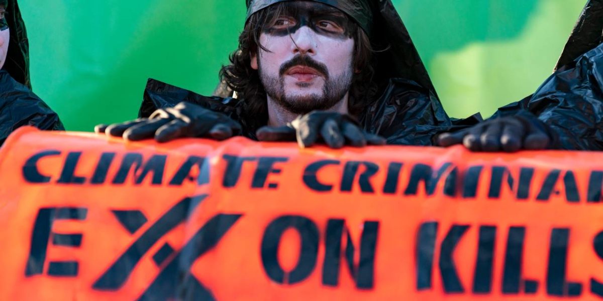 A protester holding a sign that reads Exxon kills. Exxon was aware of the damage their corporation was doing to the world, but keep that information hidden for the sake of corporate profits.