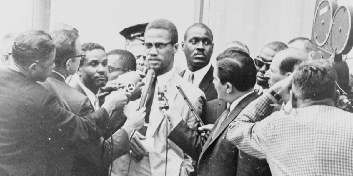 A photo of Malcolm X being interviewed by reporters.