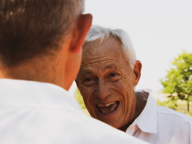 An over-the-shoulder image of a smiling senior citizen.