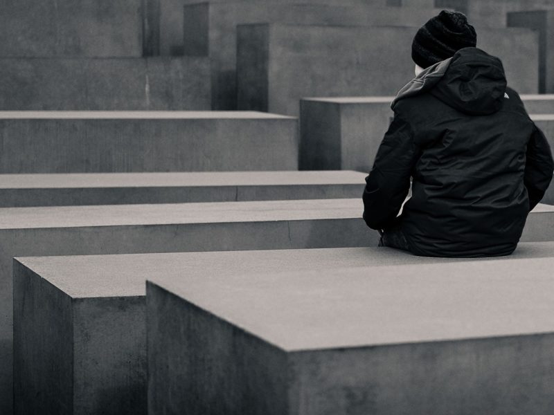 A child sits on a stone monument at the Berlin Memorial for the murdered Jews of Europe.