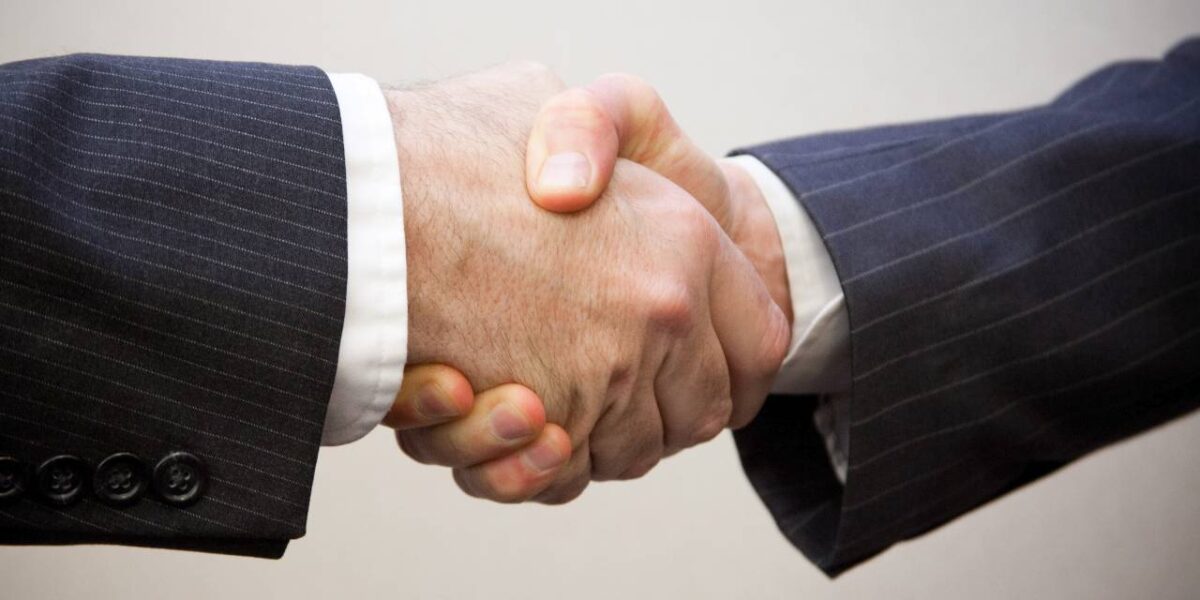 Two men in suits shaking hands.