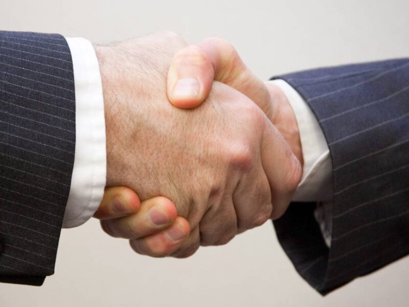 Two men in suits shaking hands.