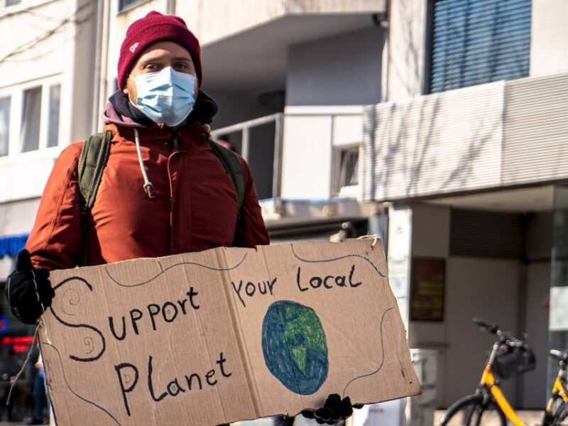 A climate protester holding a sign saying "Support your local planet."