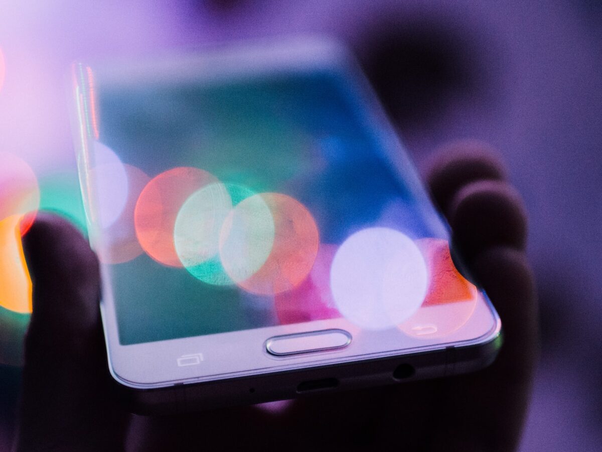 A photo of a hand holding a smartphone, source of both news and social media.