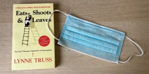 An image of the punctuation book "Eats, Shoots & Leaves" next to a surgical mask used during the COVID-19 pandemic.