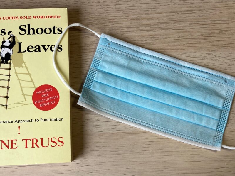 An image of the punctuation book "Eats, Shoots & Leaves" next to a surgical mask used during the COVID-19 pandemic.