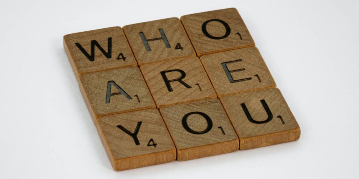 Nine square pieces from the game Scrabble spelling out the phrase "who are you?"