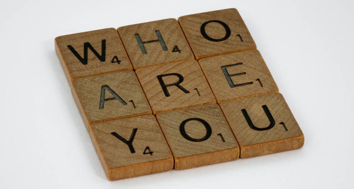 Nine square pieces from the game Scrabble spelling out the phrase "who are you?"