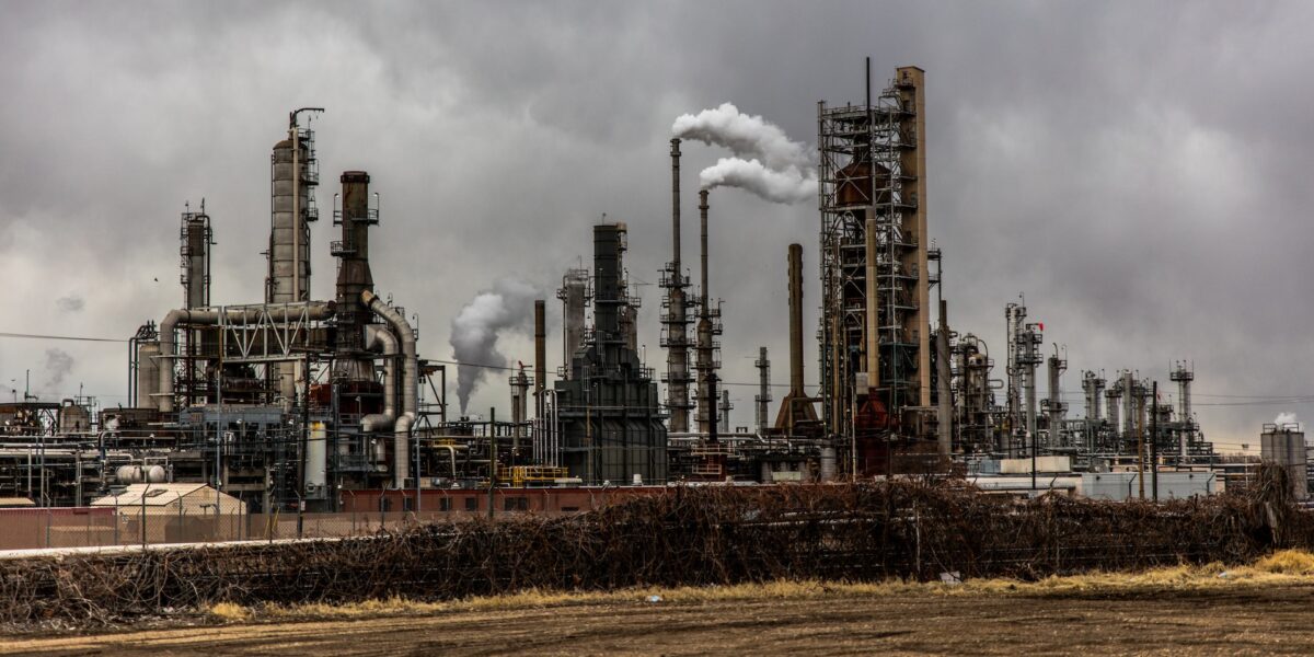 Image of an oil refinery with smoke stacks.