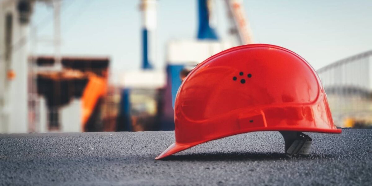 An orange workers helmet resting on a cement ground.
