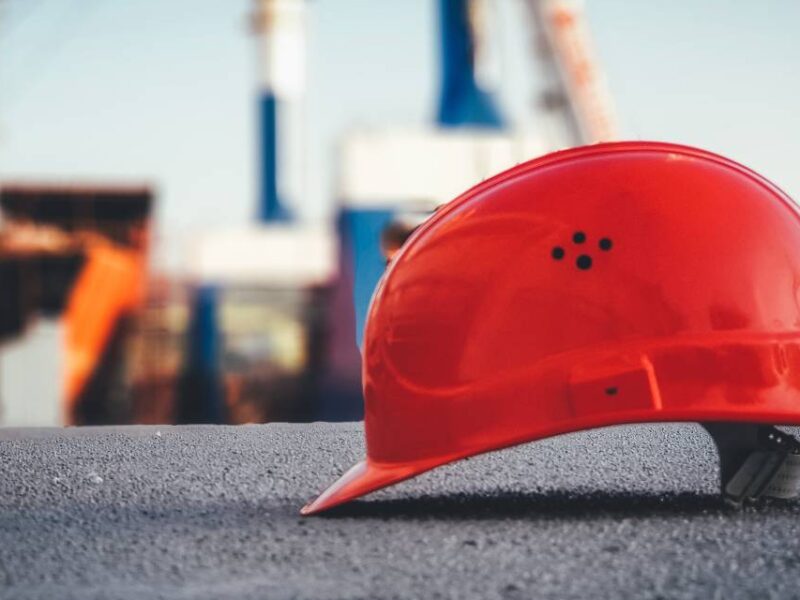 An orange workers helmet resting on a cement ground.