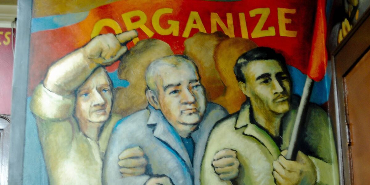 A mural showing three men holding a banner saying organize.