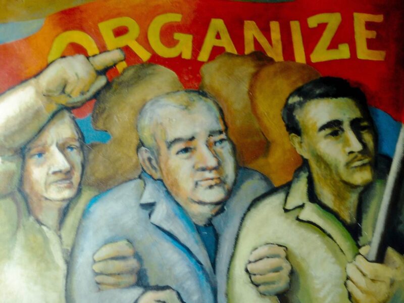 A mural showing three men holding a banner saying organize.