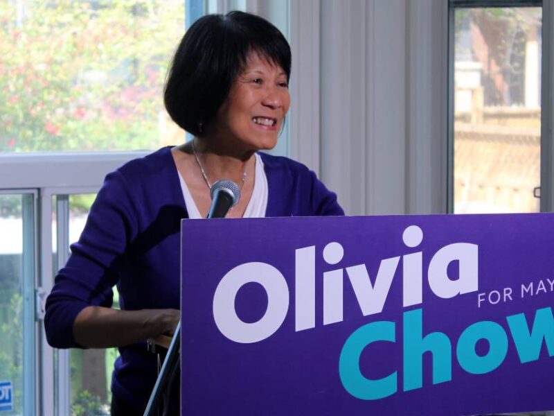 Olivia Chow standing behind a podium bearing her name.