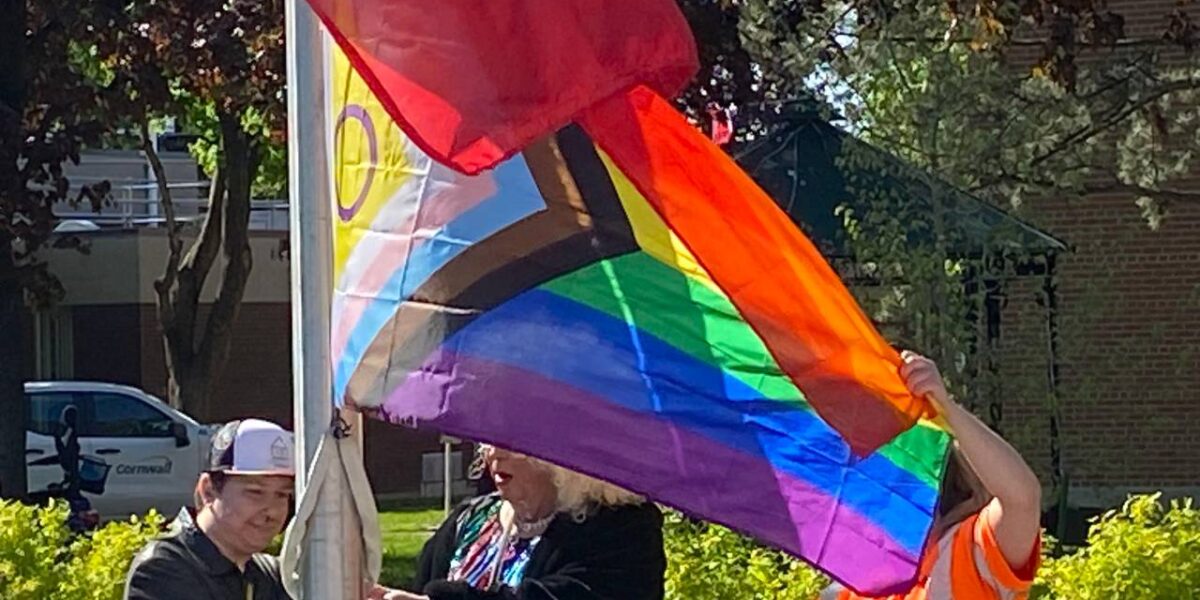 Three people raise a 2SLGBTQIA_ flag on the International Day against Transphobia, Homophobia and Biphobia in Cornwall, Ontario on Wednesday, May 17, 2023.